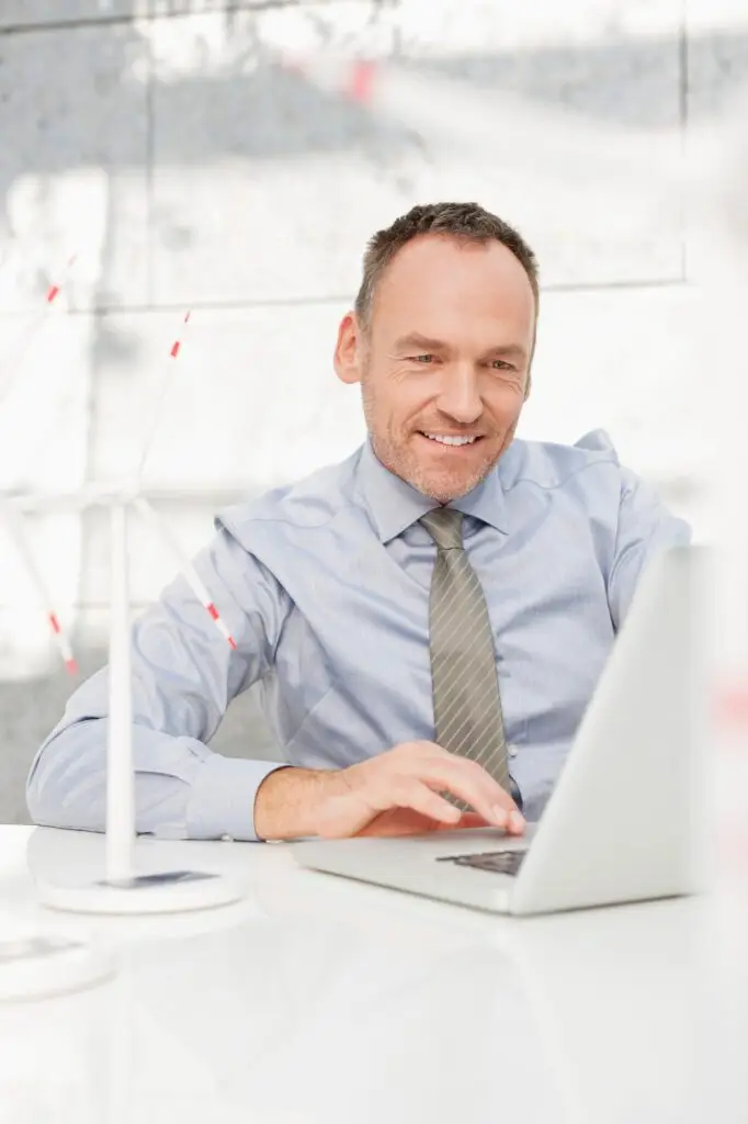 Germany, Leipzig, Businessman using laptop with wind power model